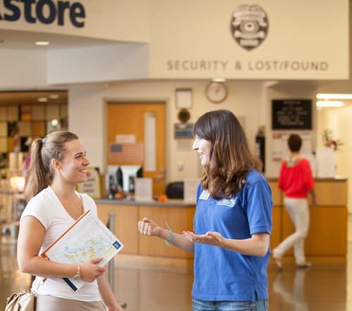 two smiling women talking in front of security reception desk